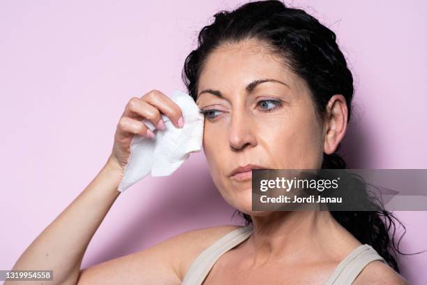 beautiful middle-aged woman removing make-up with a make-up remover wipe - woman make up face wipes not men stock pictures, royalty-free photos & images