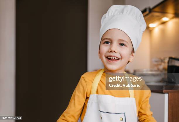 boy with the chef cap and chef uniform smiling - kid chef stock pictures, royalty-free photos & images