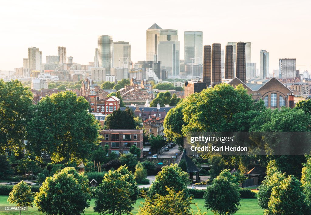 A surface level view of The Canary Wharf skyline, London at sunset from Greenwich Park - stock photo