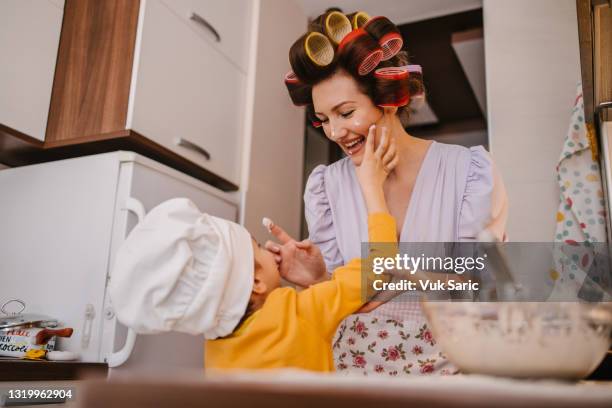 mother putting cake dough on her son's nose - krulspelden stockfoto's en -beelden