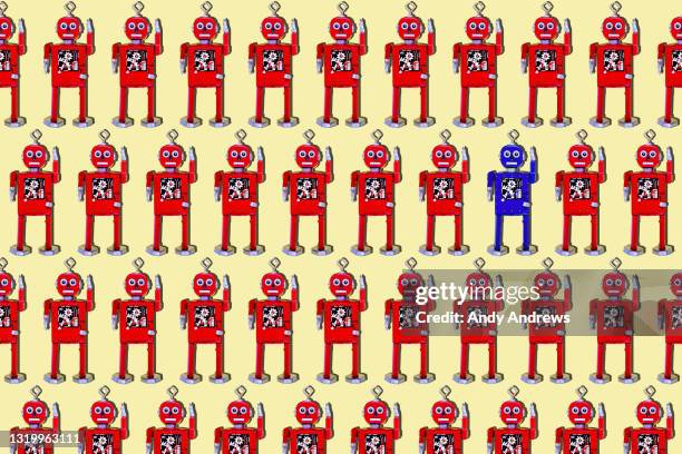 solitary blue robot in rows of red robots - wind up toy imagens e fotografias de stock