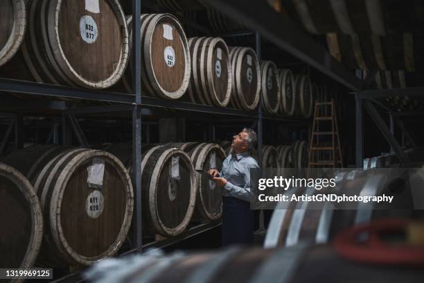 examinando barriles en bodega envejecida. - barril fotografías e imágenes de stock