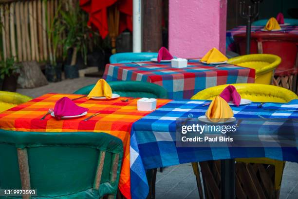 horizontal close-up view of tables with brightly colored tablecloth and chairs in a casual mexican restaurant outdoor cafe in playa del carmen, mexico - mexican restaurant outside stock pictures, royalty-free photos & images