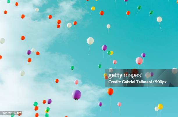 low angle view of balloons flying against blue sky - helium stockfoto's en -beelden