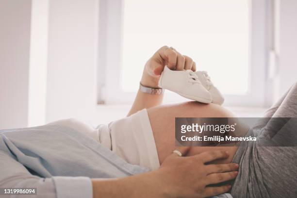 baby shoes on pregnant belly - baby booties imagens e fotografias de stock