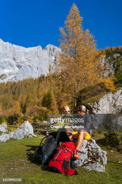 wandelend paar dat op rotsen in mooie bergen op zonnige dag rust - 40s couple sunny stockfoto's en -beelden