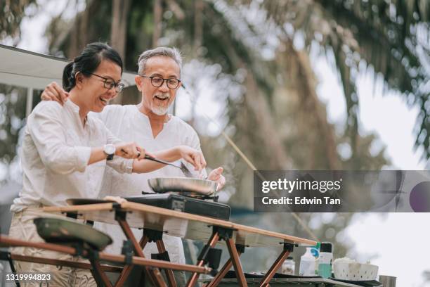 夕食を準備するキャンプでアジアの中国のシニアカップルの料理 - middle aged couple cooking ストックフォトと画像