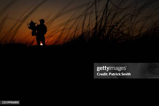 As the sunsets, Phil Mickelson of the United States celebrates with the Wanamaker Trophy on a sand dune after winning during the final round of the...