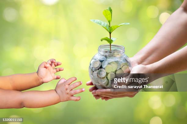 an adult is giving the child a jar with savings in the jar. - home economics ストックフォトと画像