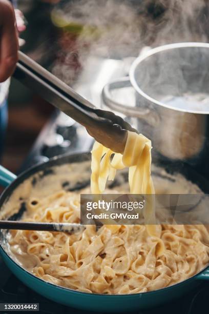 preparing fettuccine pasta alfredo - fettuccine alfredo stock pictures, royalty-free photos & images