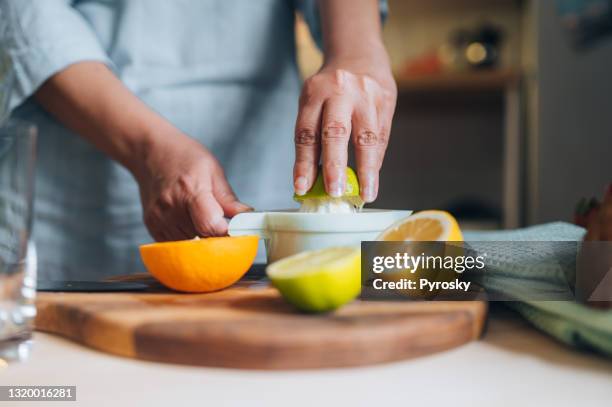 donna che stringe calce al bancone della cucina - spremere foto e immagini stock