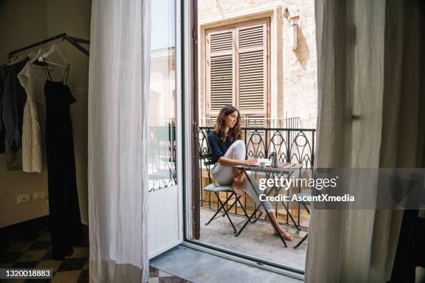 young woman  writes in journal from apartment balcony in old city street - travel writer stock pictures, royalty-free photos & images