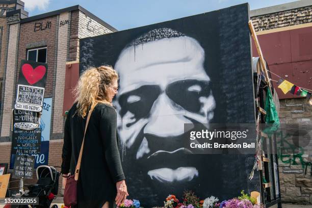 Woman stands in front of a mural of George Floyd on May 25, 2021 in Minneapolis, Minnesota. People gather in the intersection of 38th Street and...