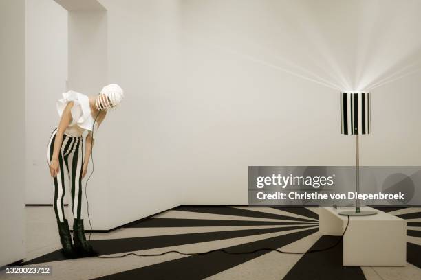 bizarre model in striped outfit and lamp - intellectual property stock-fotos und bilder