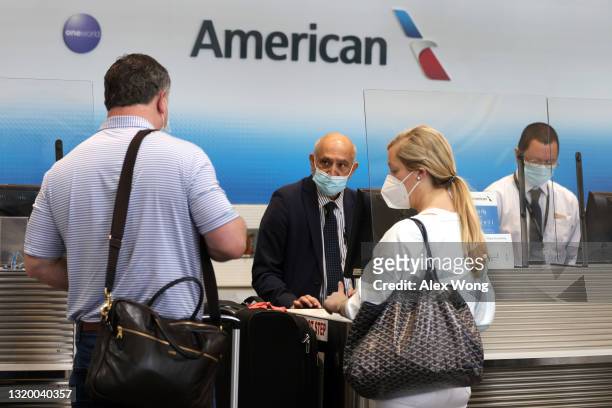 American Airlines agents help passengers to check in their flights at Ronald Reagan Washington National Airport May 25, 2021 in Arlington, Virginia....
