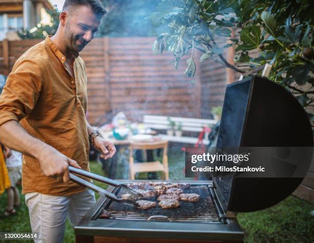 het grillen van de mens vlees voor de barbecuepartij - backyard grilling stockfoto's en -beelden