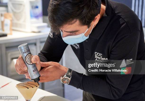 Mask-clad Barista Academy trainer Pedro Marmelo decorates a coffee beverage at Centro de Ciencia do Café of the Grupo Nabeiro - Delta Cafés, meant to...