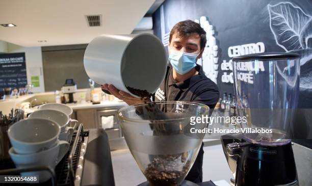 Barista Academy trainer Pedro Marmelo wears a protective mask as he puts coffee beans in the grinder before brewing expressos at Centro de Ciencia do...