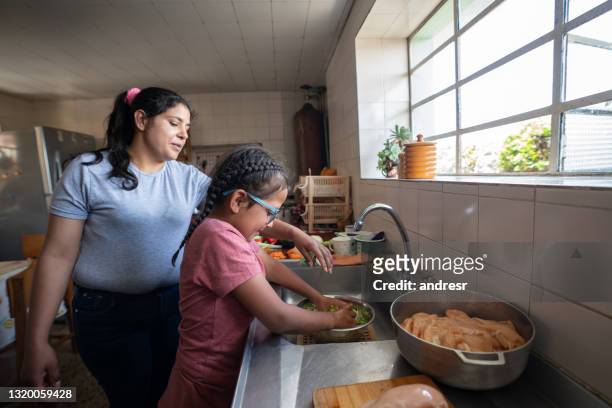 latin american mother teaching her daughter to cook - parent and child meal stock pictures, royalty-free photos & images