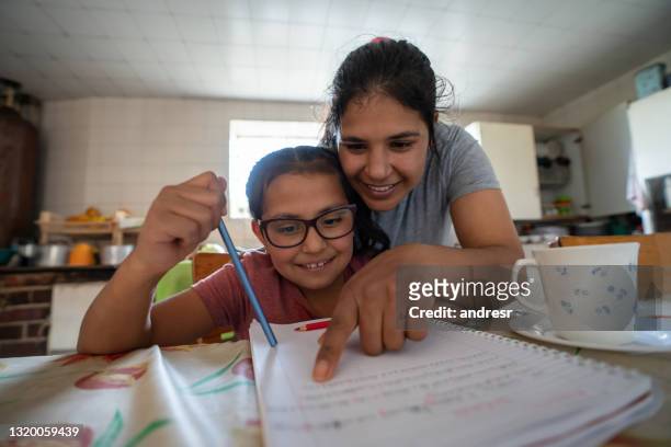 mother supervising her daughter while doing her homework - single mother poor stock pictures, royalty-free photos & images