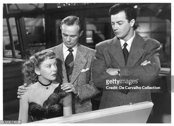 British Actress Ida Lupino sits by the piano as ‘Lily Stevens’, Actor Richard Widmark as ‘Jefferson T Jefty Robbins’ and Hungarian Actor Cornel Wilde...