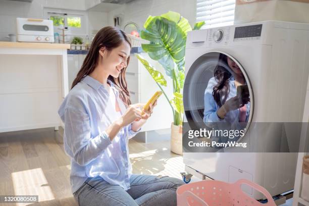 woman use smartphone control washer - washing machine stock pictures, royalty-free photos & images
