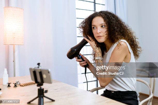 krullend haarvrouw drogend haar - airing stockfoto's en -beelden