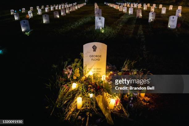 Candles illuminate a makeshift headstone for George Floyd at the Say Their Names Cemetery on May 25, 2021 in Minneapolis, Minnesota. People gathered...
