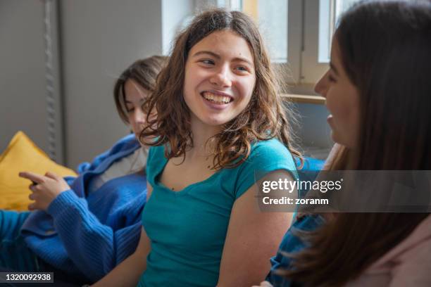 young women talking excitedly on the sofa and smiling - ouvir às escondidas imagens e fotografias de stock