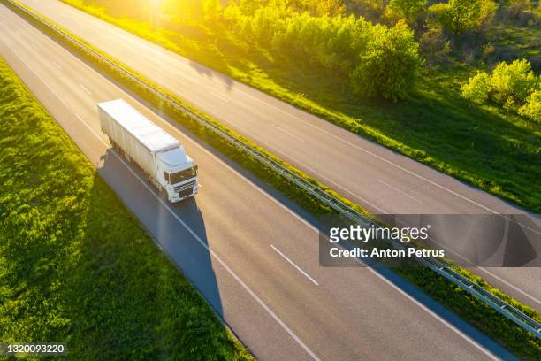 aerial view of truck driving on asphalt road along the green fields in rural landscape. - semi truck stock pictures, royalty-free photos & images