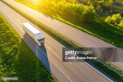 Aerial view of truck driving on asphalt road along the green fields in rural landscape. Aerial view of truck driving on asphalt road along the green fields in rural landscape.