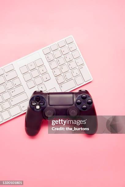 high angle view of game controller and computer keyboard on pink background - joy stick stock pictures, royalty-free photos & images