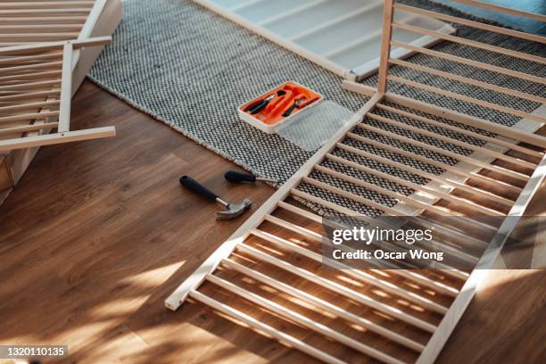 young father assembling baby cot at home - fabricantes de muebles de artesania fotografías e imágenes de stock