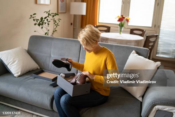 a woman opens and inspects her new boots after receiving home  delivery - shopping disappointment stock pictures, royalty-free photos & images
