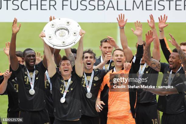 Robert Lewandowski of Bayern Muenchen lifts the Bundesliga Meisterschale Trophy in celebration with players following the Bundesliga match between FC...