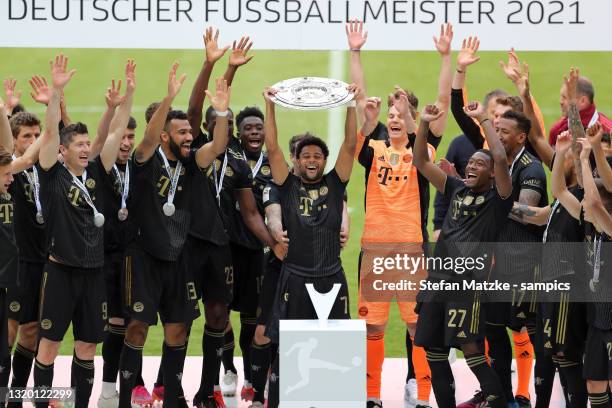 Serge Gnabry of Bayern Muenchen lifts the Bundesliga Meisterschale Trophy in celebration with players following the Bundesliga match between FC...