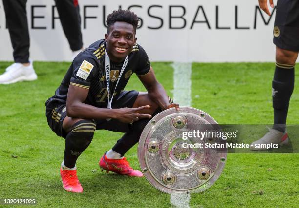 Alphonso Davies of Bayern Muenchen lifts the Bundesliga Meisterschale Trophy following the Bundesliga match between FC Bayern Muenchen and FC...