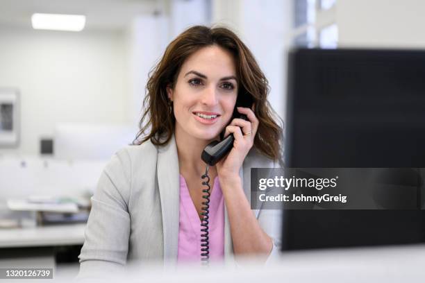 mujer adulta mediana usando teléfono en la oficina - telephone receiver fotografías e imágenes de stock