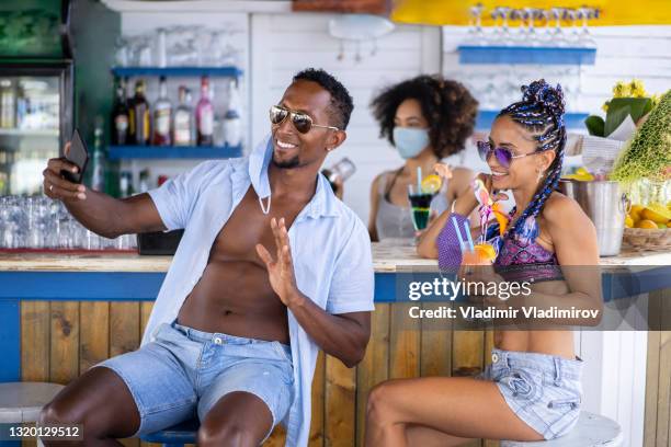 paar dat selfies in een de zomerbar in voorwaarden van coronavirus maakt - black people cocktail party stockfoto's en -beelden