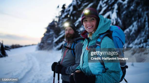 couple with headlamps hiking in winter nature at sunset, looking at camera. - hoofdlamp stockfoto's en -beelden