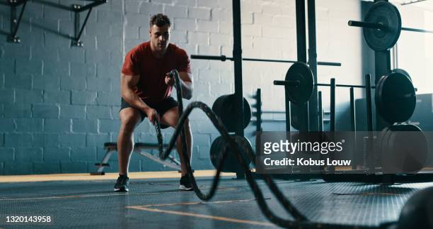 shot of a young man working out with battle ropes at the gym - man studio shot stock pictures, royalty-free photos & images