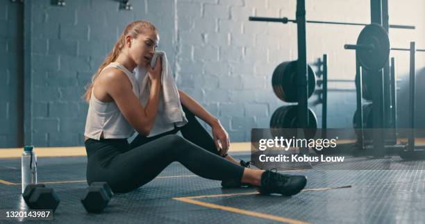 shot of a young woman drying her face after an intense workout at the gym - tough woman stock pictures, royalty-free photos & images