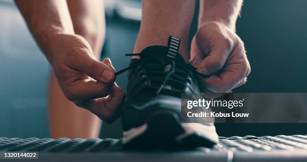 colpo ritagliato di un uomo irriconoscibile legando i lacci delle scarpe in palestra - shoes man foto e immagini stock