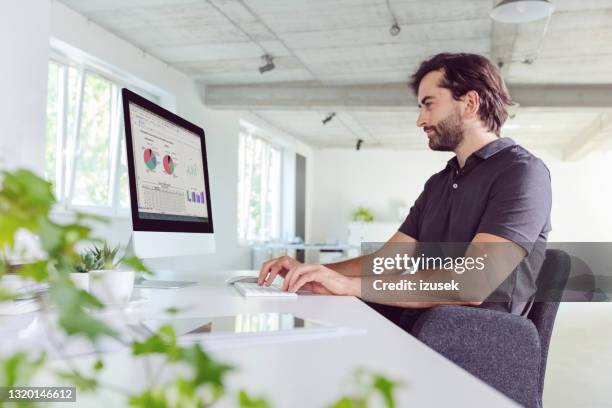 hombre trabajando en la oficina - camisa de polo fotografías e imágenes de stock