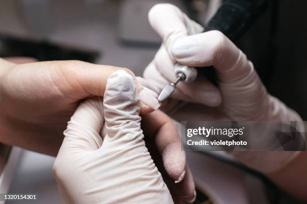 manicure master using an electric nail file to remove cuticles in the beauty salon - coronavirus moldova stock pictures, royalty-free photos & images