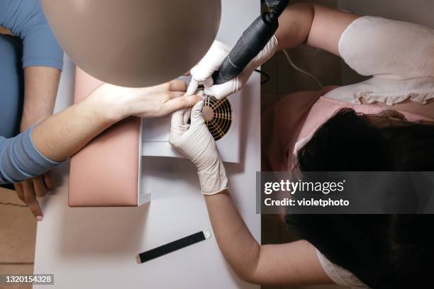 manicure master using an electric nail file to remove cuticles in the beauty salon - coronavirus moldova stock pictures, royalty-free photos & images