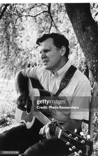 View of American Bluegrass musician Doc Watson as he plays guitar outside his home, Deep Gap, North Carolina, 1964.