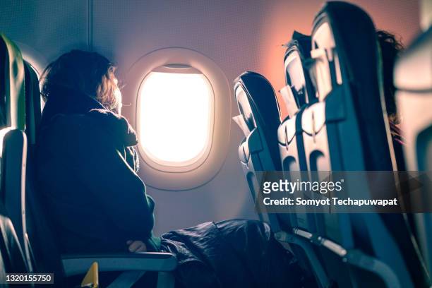 asian female traveller sit relax looking of of airplane window - flugzeugsitz stock-fotos und bilder
