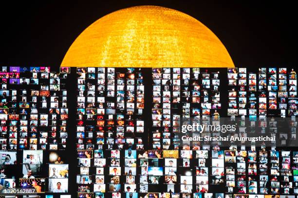 Large screen shows devotees remotely participating in the ceremony by praying via Zoom application during Vesak Day celebration at Wat Phra...
