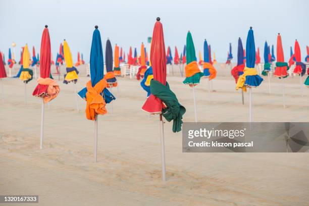 multicolored parasols on a beach . - deauville beach stock pictures, royalty-free photos & images